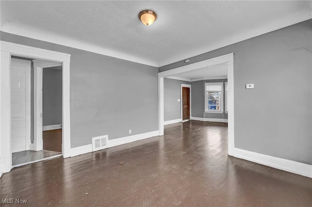 unfurnished room with finished concrete flooring, baseboards, visible vents, and a textured ceiling