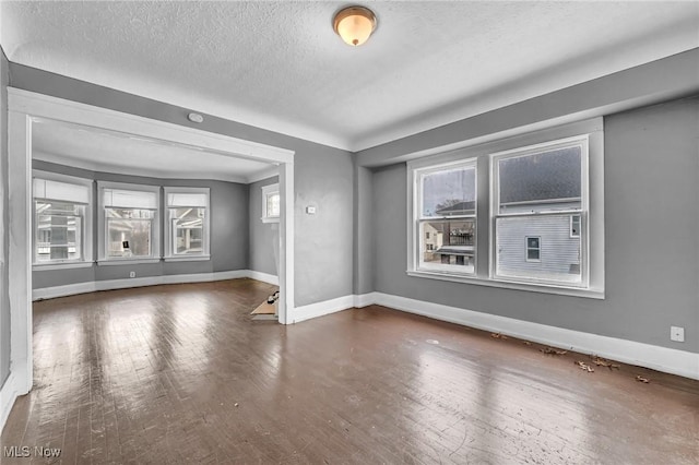 unfurnished room featuring a textured ceiling, baseboards, and hardwood / wood-style flooring