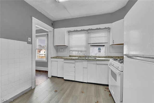 kitchen featuring white appliances, a sink, light wood-style floors, and white cabinets