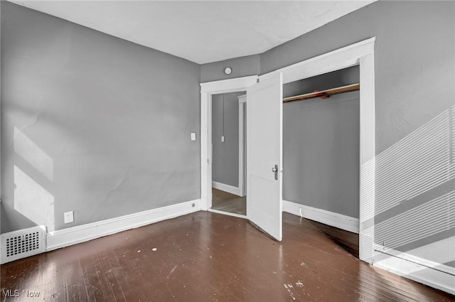 unfurnished bedroom with baseboards, a closet, visible vents, and wood finished floors