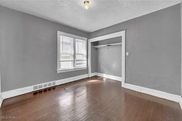 unfurnished bedroom featuring baseboards, a closet, visible vents, and hardwood / wood-style floors