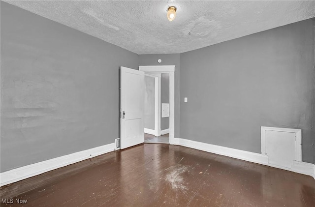 unfurnished room with a textured ceiling and baseboards