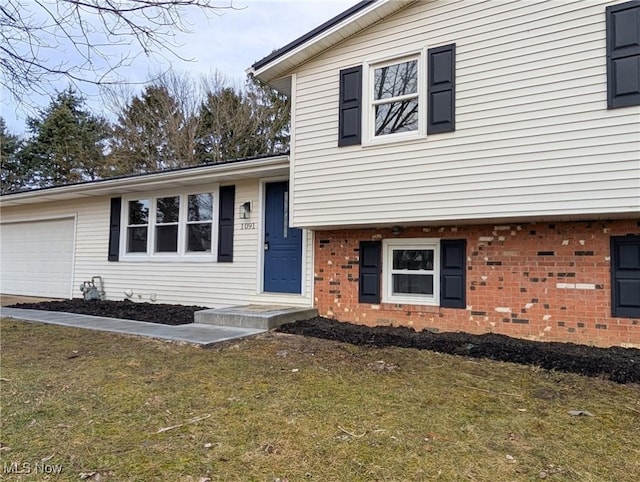 split level home featuring a garage, a front lawn, and brick siding