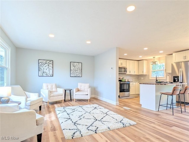 living area with light wood-type flooring, baseboards, and recessed lighting