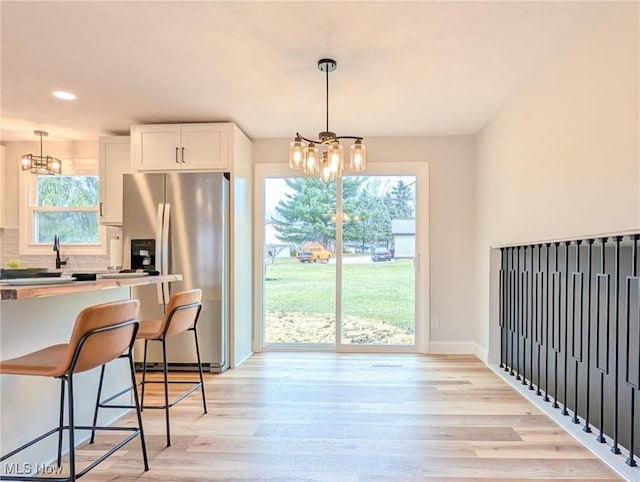 kitchen featuring a chandelier, white cabinets, light wood finished floors, and stainless steel fridge with ice dispenser