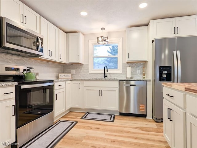 kitchen featuring a notable chandelier, light wood-style flooring, decorative backsplash, appliances with stainless steel finishes, and white cabinets