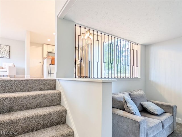 staircase featuring carpet flooring, a textured ceiling, and baseboards