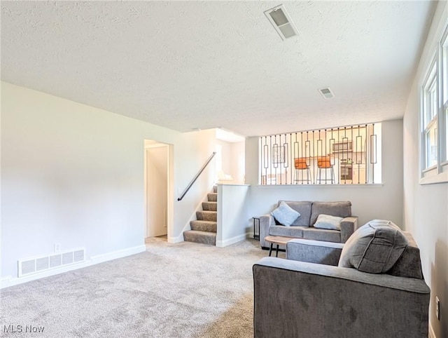 living area featuring baseboards, stairs, visible vents, and carpet flooring