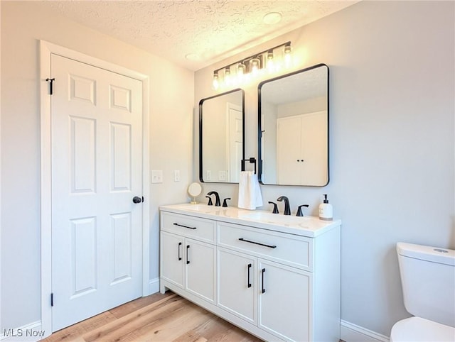 bathroom featuring a textured ceiling, wood finished floors, a sink, and toilet