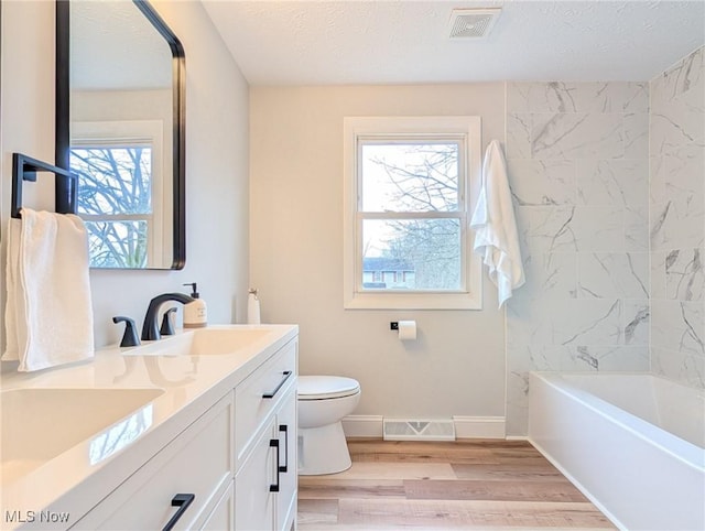 full bathroom with visible vents, a sink, toilet, and wood finished floors