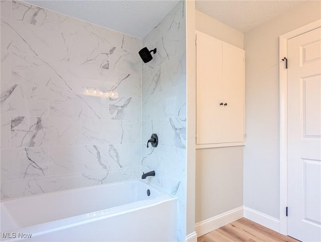 full bathroom with a textured ceiling, baseboards, wood finished floors, and shower / bathtub combination