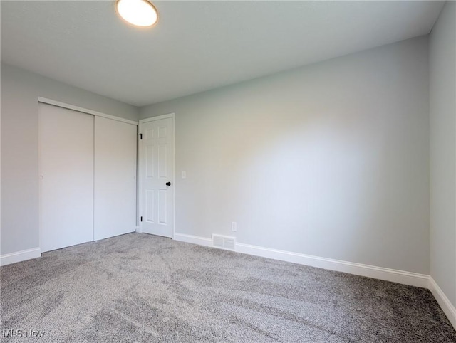 unfurnished bedroom with a closet, carpet, visible vents, and baseboards