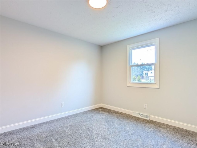 carpeted spare room with a textured ceiling, visible vents, and baseboards