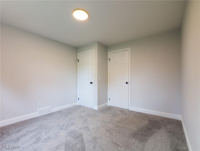 unfurnished room with carpet floors, baseboards, and visible vents