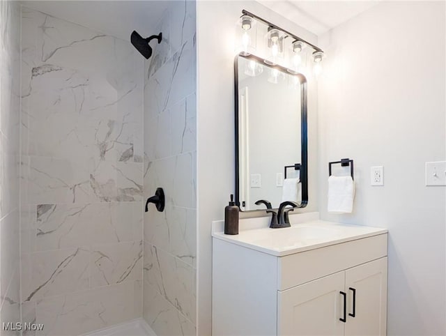 full bath featuring a tile shower and vanity