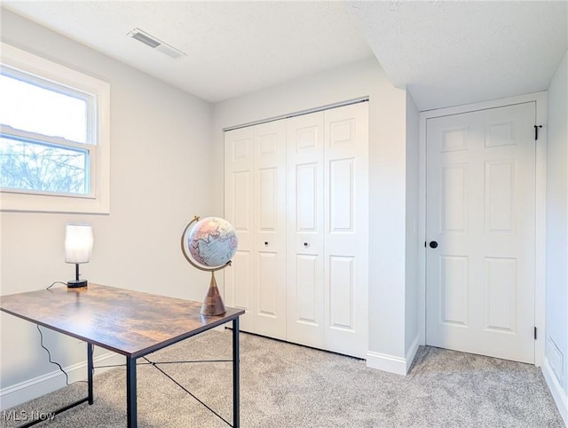 unfurnished office with baseboards, visible vents, a textured ceiling, and light colored carpet