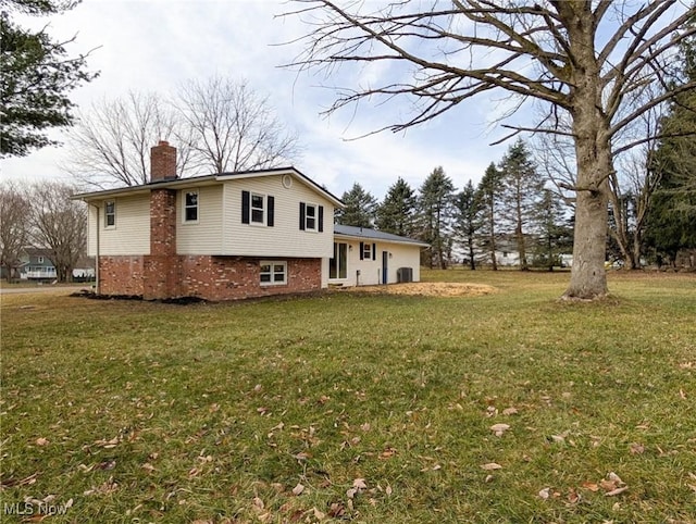 view of front of home featuring brick siding, a chimney, and a front yard