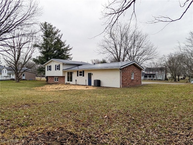 view of front facade with brick siding, a front lawn, and central AC unit