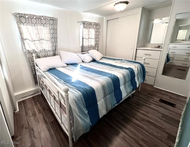 bedroom featuring a closet, dark wood finished floors, and visible vents