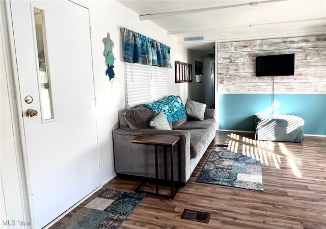 living room with visible vents, beamed ceiling, and wood finished floors