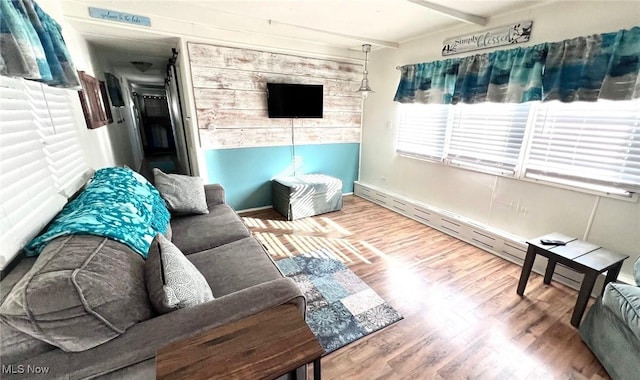 living room featuring wood finished floors, beam ceiling, and baseboards