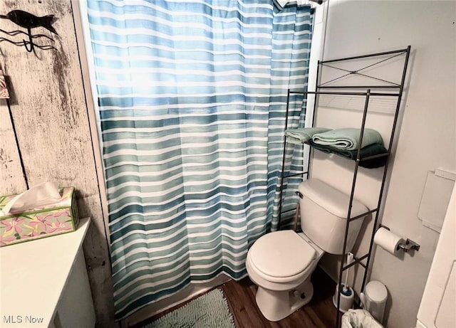 full bathroom featuring curtained shower, toilet, and wood finished floors