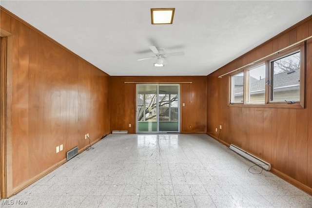 empty room with wooden walls, visible vents, a baseboard radiator, ceiling fan, and tile patterned floors