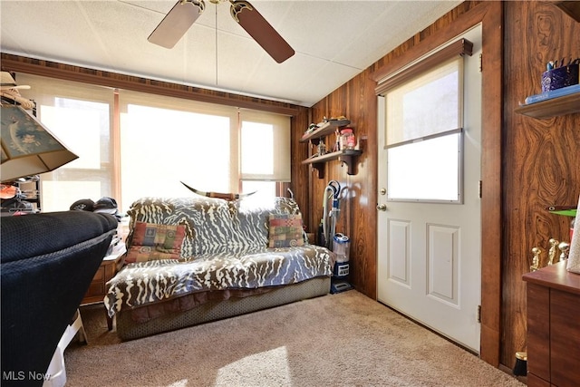 carpeted living area featuring ceiling fan and wooden walls