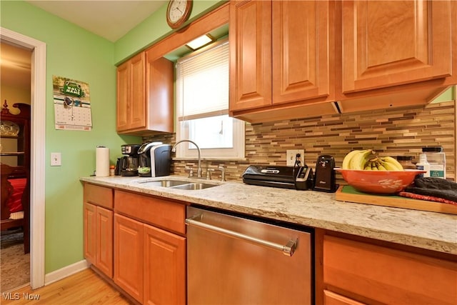 kitchen featuring dishwasher, light stone counters, a sink, and decorative backsplash