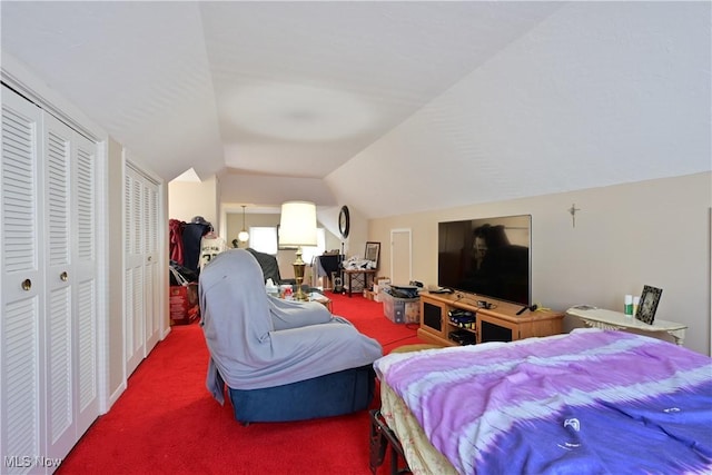 carpeted bedroom featuring lofted ceiling and multiple closets