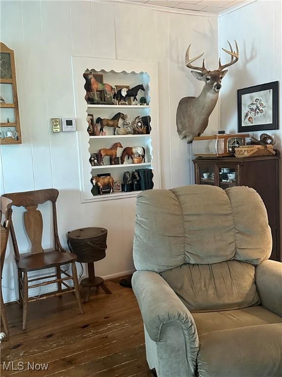 living area with hardwood / wood-style flooring and a decorative wall