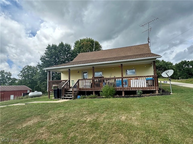 rear view of house with covered porch, a shingled roof, and a yard