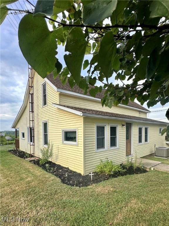 view of home's exterior with cooling unit and a lawn