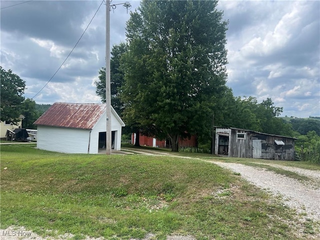 view of front of house featuring a garage, a front lawn, metal roof, and an outbuilding