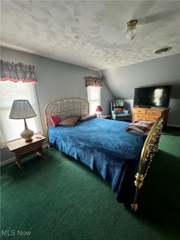 bedroom with a textured ceiling, carpet flooring, visible vents, baseboards, and vaulted ceiling