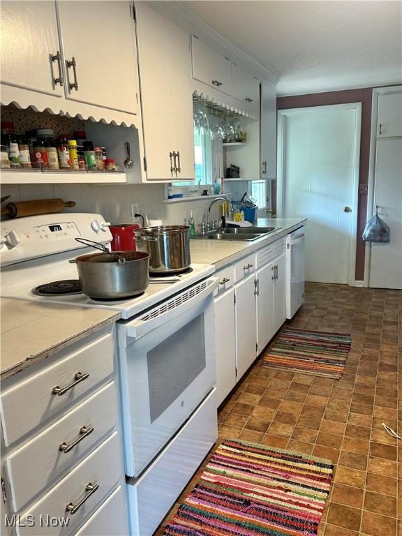 kitchen with white appliances, light countertops, a sink, and white cabinets