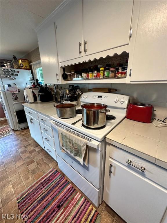 kitchen featuring tile countertops, white appliances, white cabinets, backsplash, and open shelves