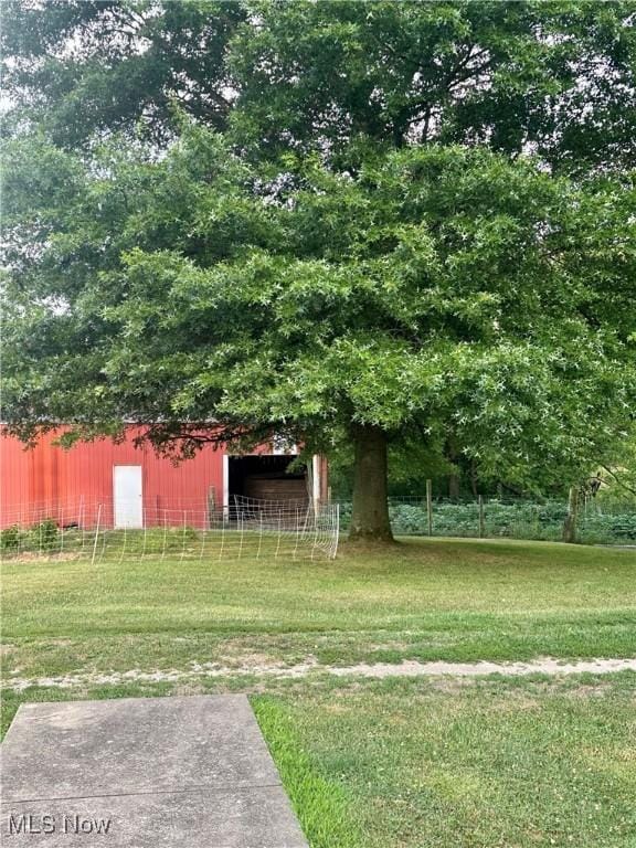 view of yard featuring an outbuilding, a pole building, and fence