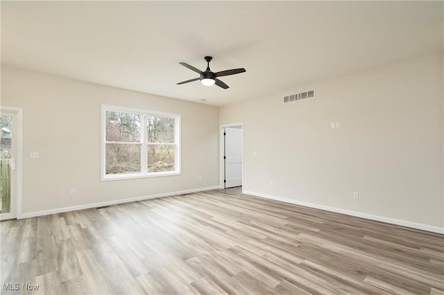 empty room featuring a healthy amount of sunlight, light wood-style flooring, visible vents, and baseboards