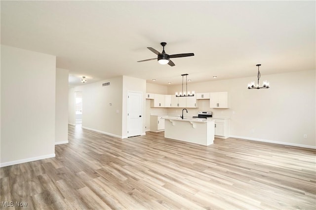 unfurnished living room with light wood finished floors, baseboards, visible vents, a sink, and ceiling fan with notable chandelier