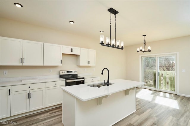 kitchen with an island with sink, light wood finished floors, stainless steel electric range, and a sink