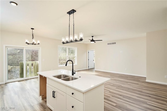 kitchen featuring visible vents, a sink, hanging light fixtures, and light wood finished floors