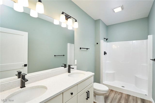 full bathroom featuring toilet, a shower, a sink, and wood finished floors