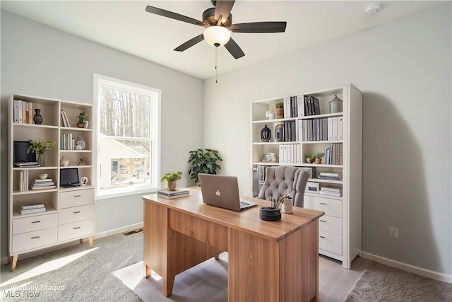 office area with a ceiling fan and baseboards