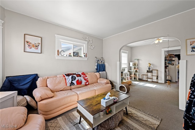 carpeted living room with arched walkways and ceiling fan