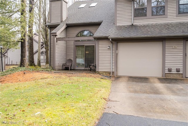 entrance to property with a yard, a chimney, a shingled roof, a garage, and driveway