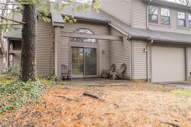 entrance to property with a garage and roof with shingles