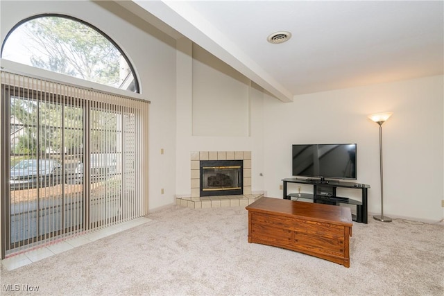 carpeted living area with a high ceiling, visible vents, beamed ceiling, and a tile fireplace