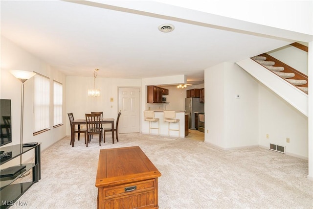 living area featuring light carpet, stairway, visible vents, and a chandelier