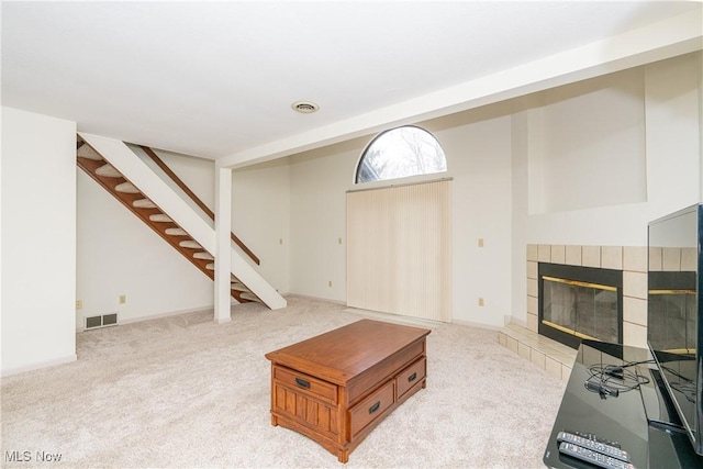 living area featuring carpet, visible vents, a fireplace, and stairs